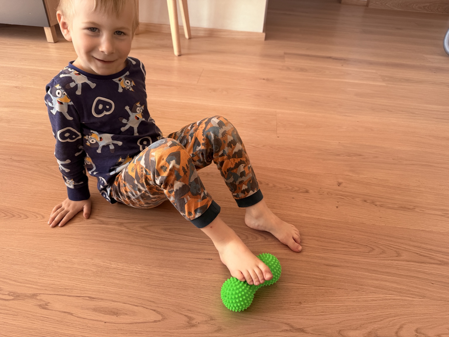 Dieťa v sede kotúľa zelený masážny duoball pod chodidlom