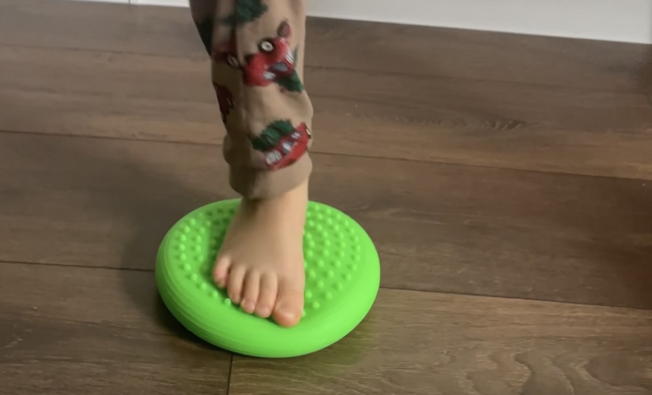 Detail chodidla dieťaťa pri hre na zelenom balančnom vankúši mini